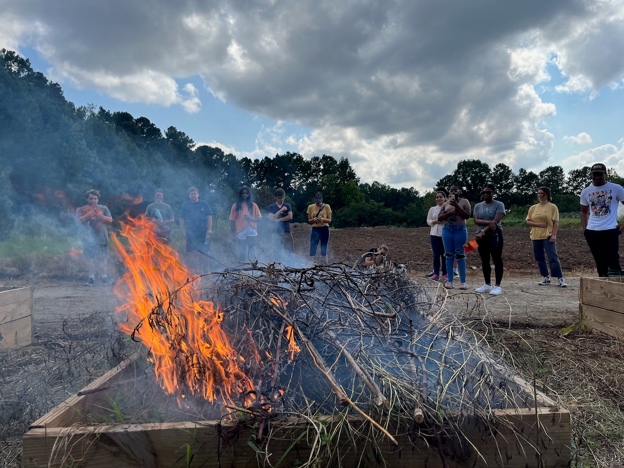 students observing a controlled burn inside a raised bed