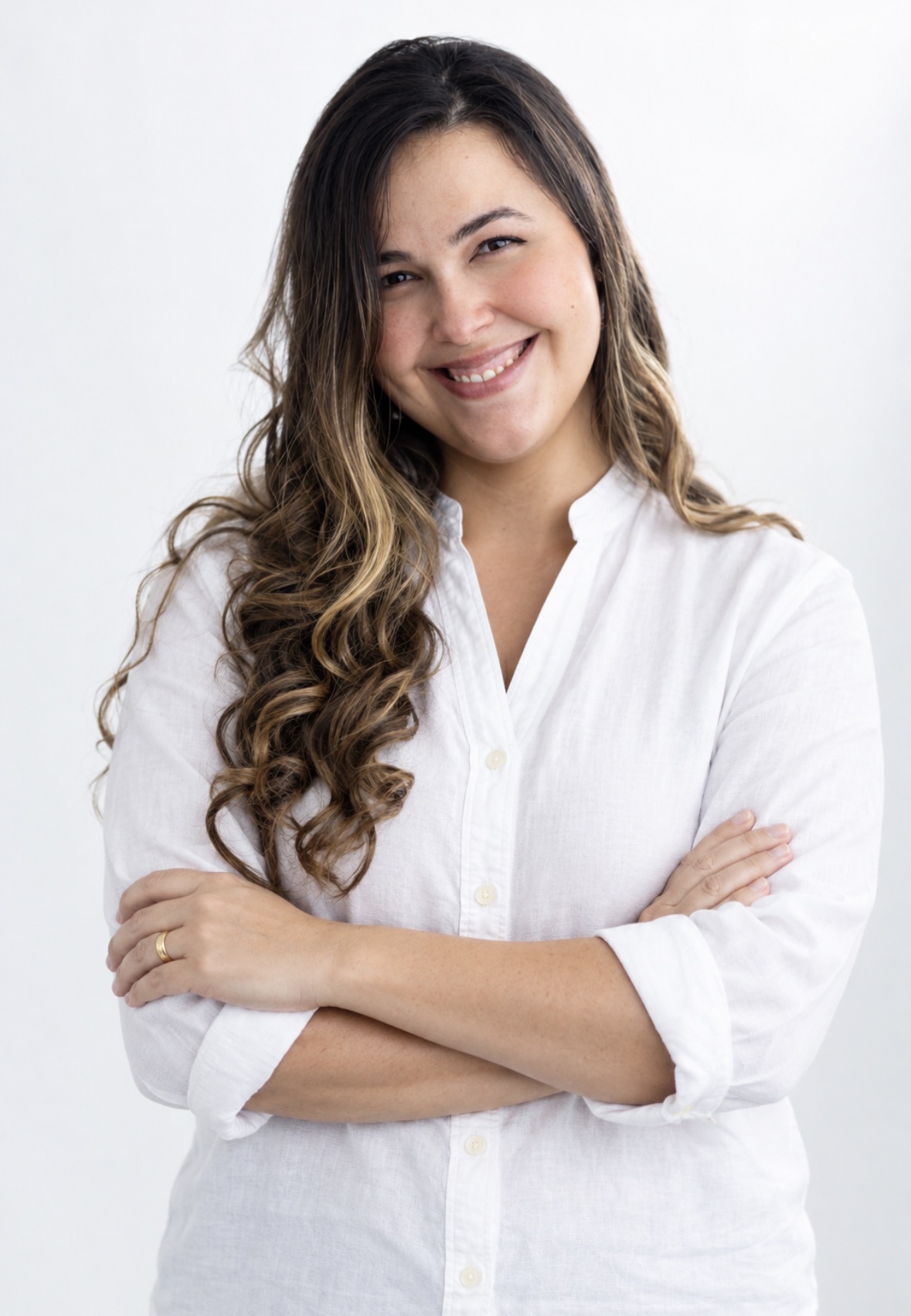 Prof. Souza is wearing a white button shirt and is smiling with her arms crossed.